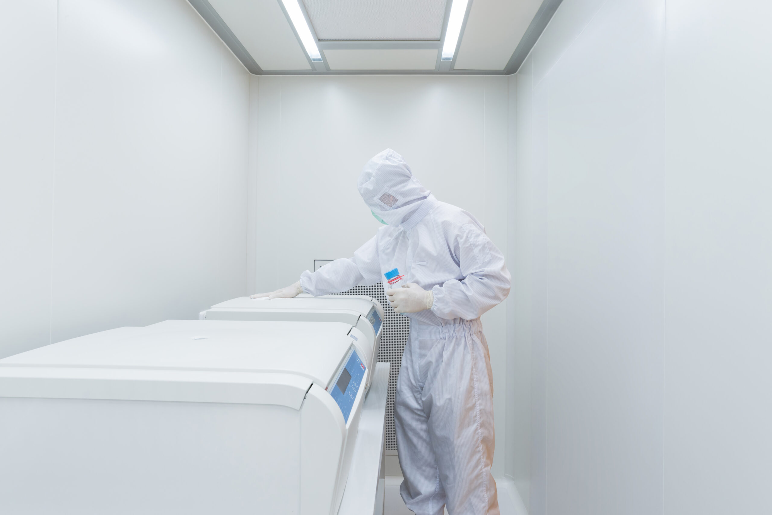 A person in a white coverall standing next to a washer